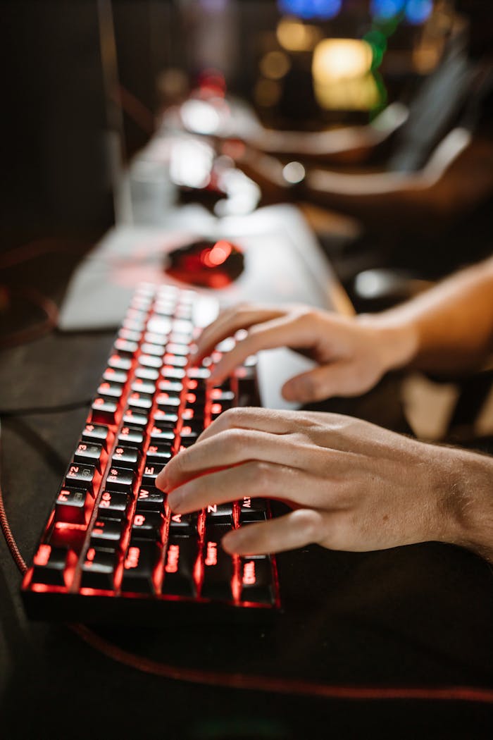 A close-up shot of a gamers hands using a mechanical gaming keyboard with red backlighting.